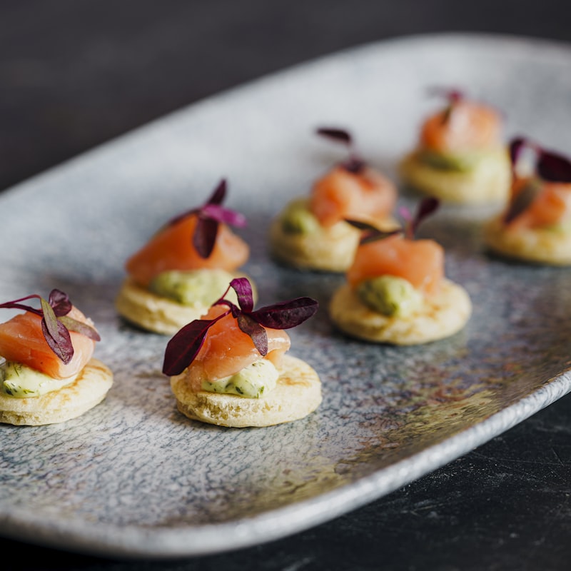 Salmon canapés garnished with petals on a stone platter