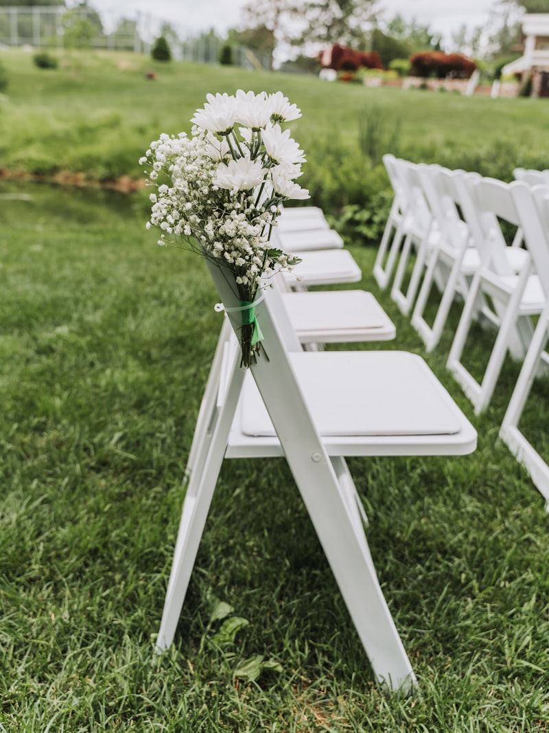 White ceremony chairs and floral arrangements set on a lawn