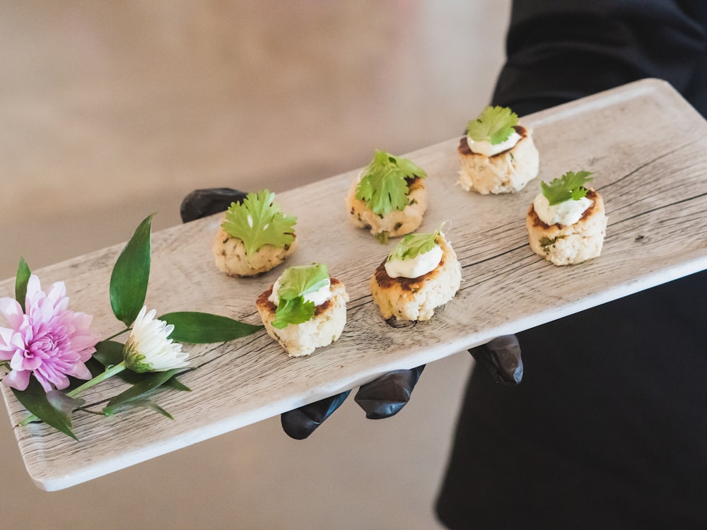 A server presenting canapés on a wooden board