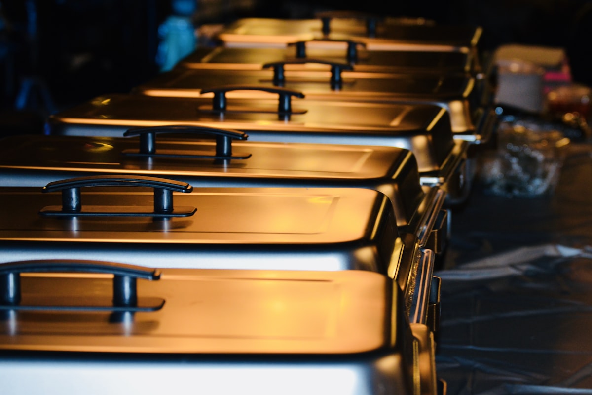 A row of brass chafing dishes along a buffet line