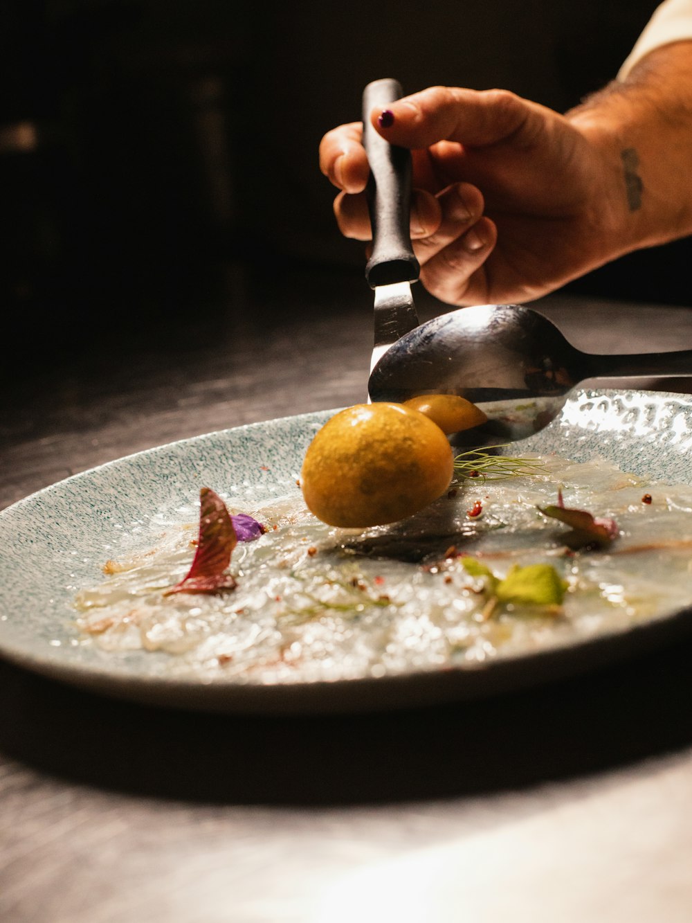 A chef finishing a plated course by hand at the pass
