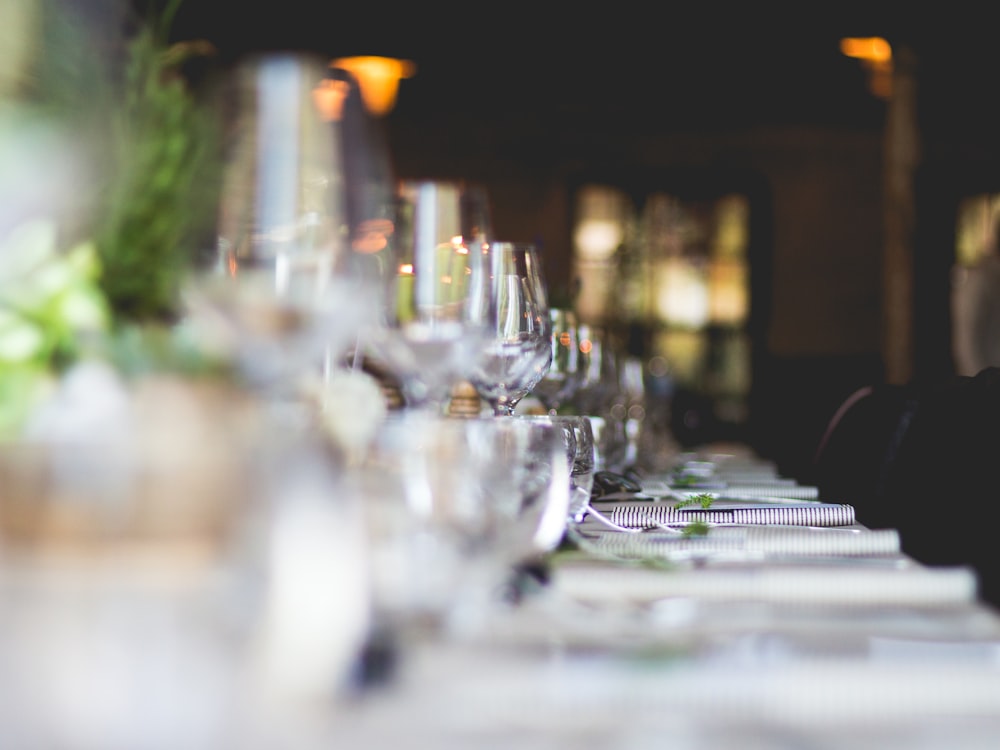 A row of wine glasses along a banquet table being set